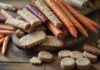Gesunde Leckerlis für Hunde: So geht Naschen richtig! A hyperrealistic close-up of various healthy, natural dog treats scattered on a rustic wooden table. Include carrot sticks, baked biscuits, and dried meat pieces. Soft, natural lighting highlights the textures, with no text.