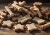 A hyperrealistic close-up of a variety of dog treats, including baked biscuits, chewy sticks, and training treats, scattered on a rustic wooden table, sunlight streaming in, no text
