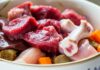 Katzen BARF Plan erstellen: So füttern Sie Ihre Katze roh & gesund! Hyperrealistic close-up of a vibrant, perfectly prepared cat BARF meal in a ceramic bowl. Raw beef, chicken pieces, small bones, liver, and diced carrots are arranged. Soft natural window light, intricate textures of fresh meat are visible, shallow depth of field. Eye-level shot, artifact-free, no text.