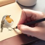 Hyperrealistic close-up of a hand delicately sketching a vibrant robin in a worn leather sketchbook. Soft, diffused natural light from a nearby window illuminates the textured paper and the subtle details of the hand's skin and pencil grip. Focus on the intricate feather details of the unfinished robin drawing, emphasizing depth and shading. No text.